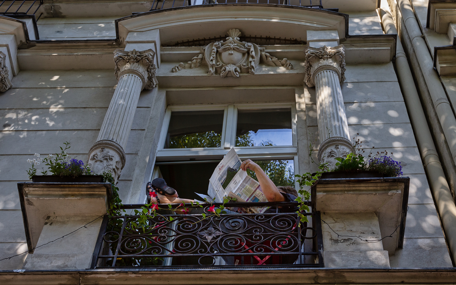 Mann auf Balkon liest Zeitung